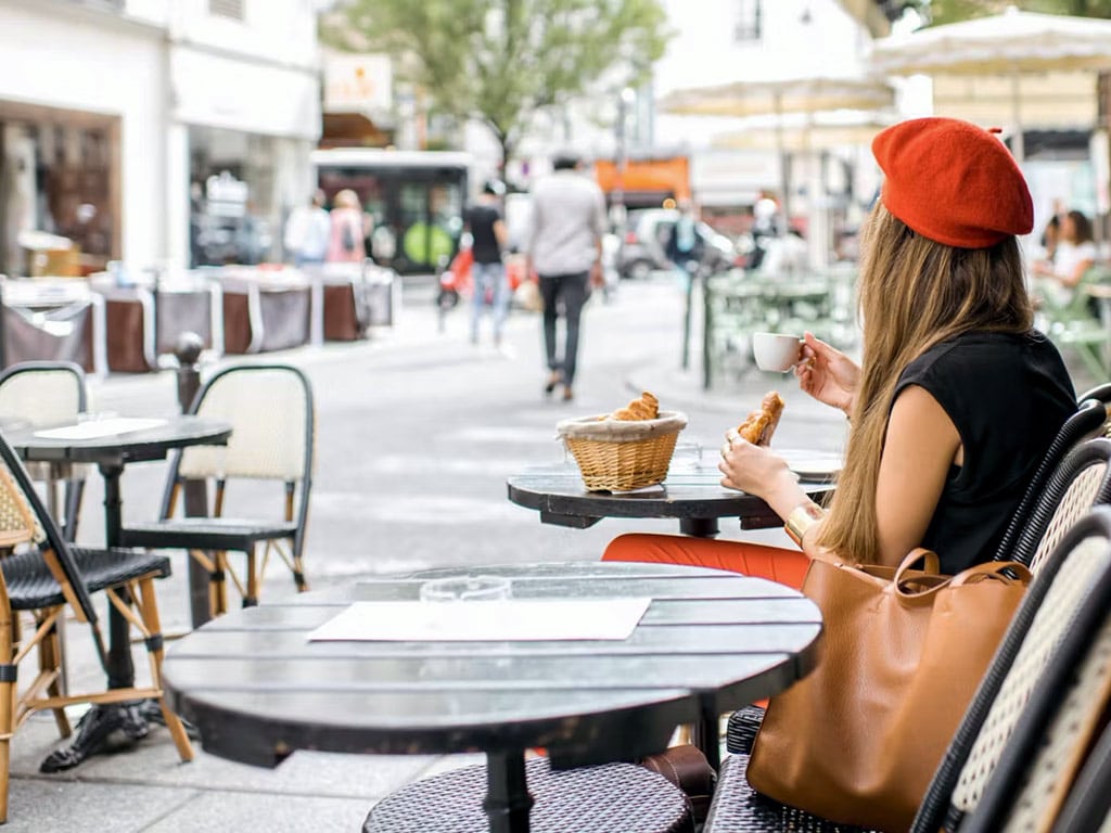 French girl eating baguette and croissant on a terrace in Paris • Paris Whatsup